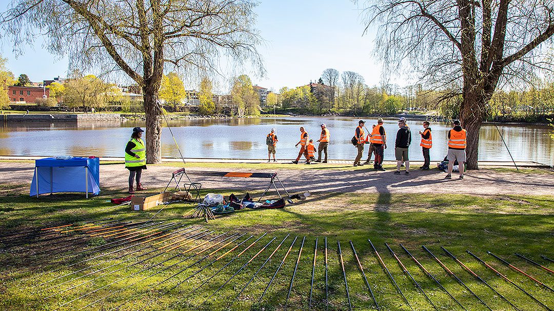 Kalastuksenohjaajat valmiina ja odottamassa lapsia saapumaan Valtakunnallisen kalastuspäivän tapahtumaan Helsingin Vanhankaupunginkosken rannalla.