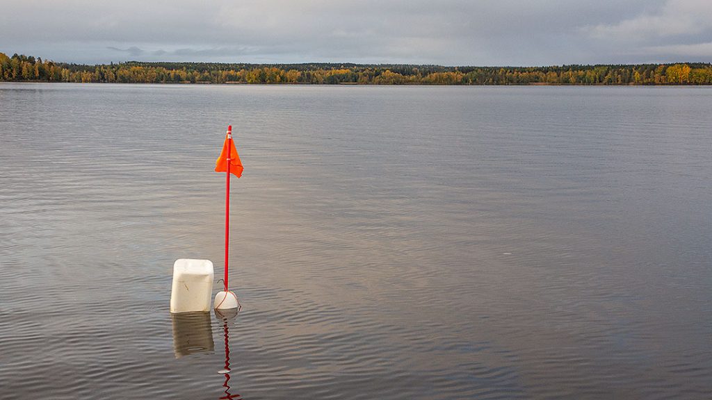 Lipulla ja koholla merkitty kalaverkko syksyisellä järvellä.
